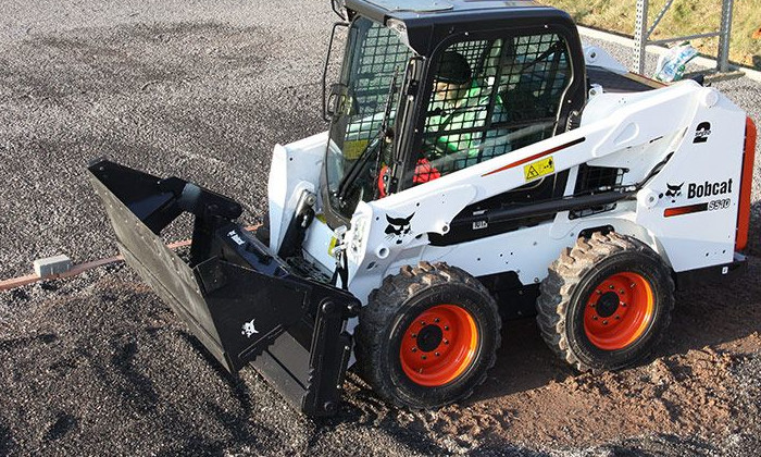 Bobcat S510 beim Verteilen udn Steuen von Kies mit Vier-In-Eins-Schaufel