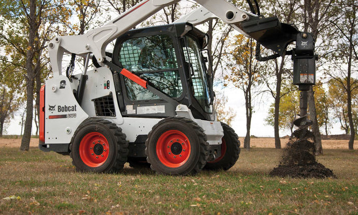 Bobcat S570 bei Asphaltarbeiten mit Erdbohrer im GaLaBau