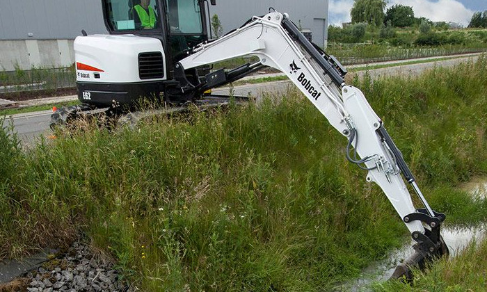 Bobcat E62 mit Grabenräumlöffel bei Arbeiten am Straßenrand mit ausgeschwenktem Arm